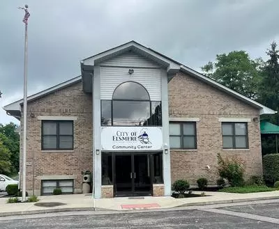 Outside of the Community Center with a parking lot in front and trees in the background