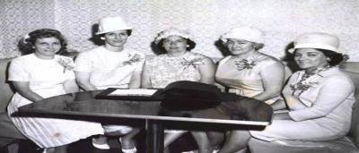 5 women sitting at a table while wearing all white