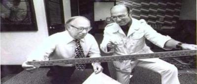 two older men are looking at a wooden ruler